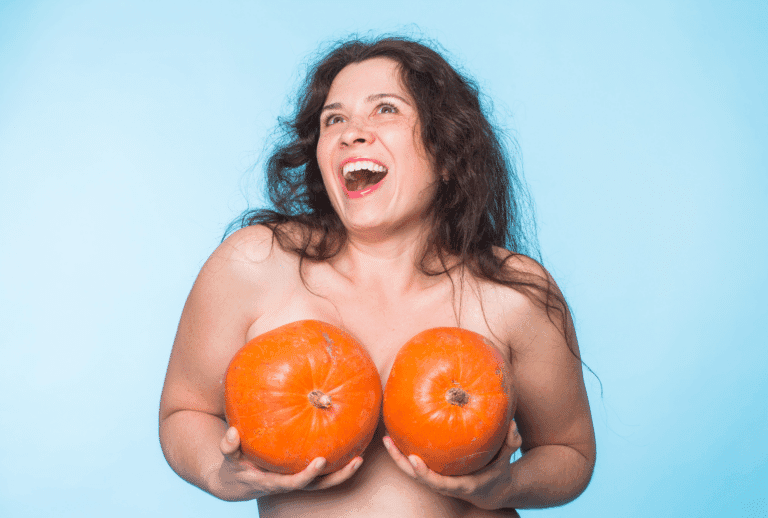 Femme souriante tenant des citrouilles devant elle