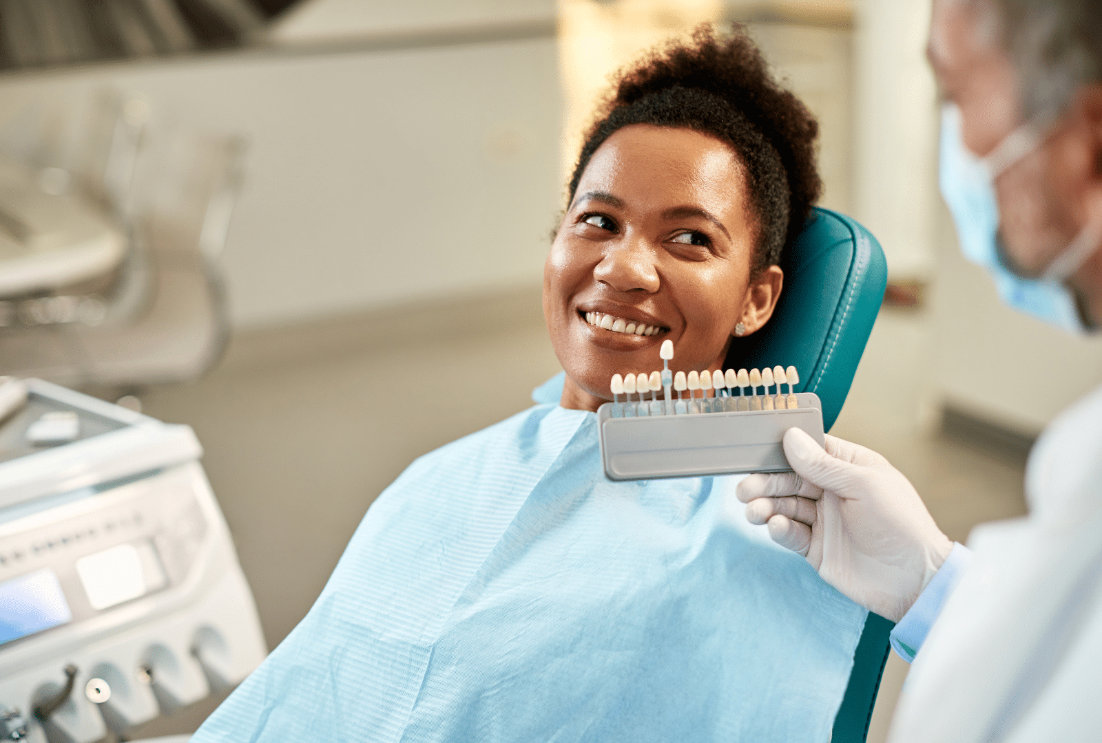 Patiente comparant la teinte de ses dents avec un nuancier avant la pose de facettes dentaires.