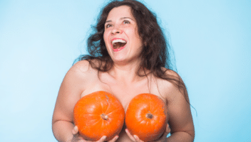 Femme souriante tenant des citrouilles devant elle