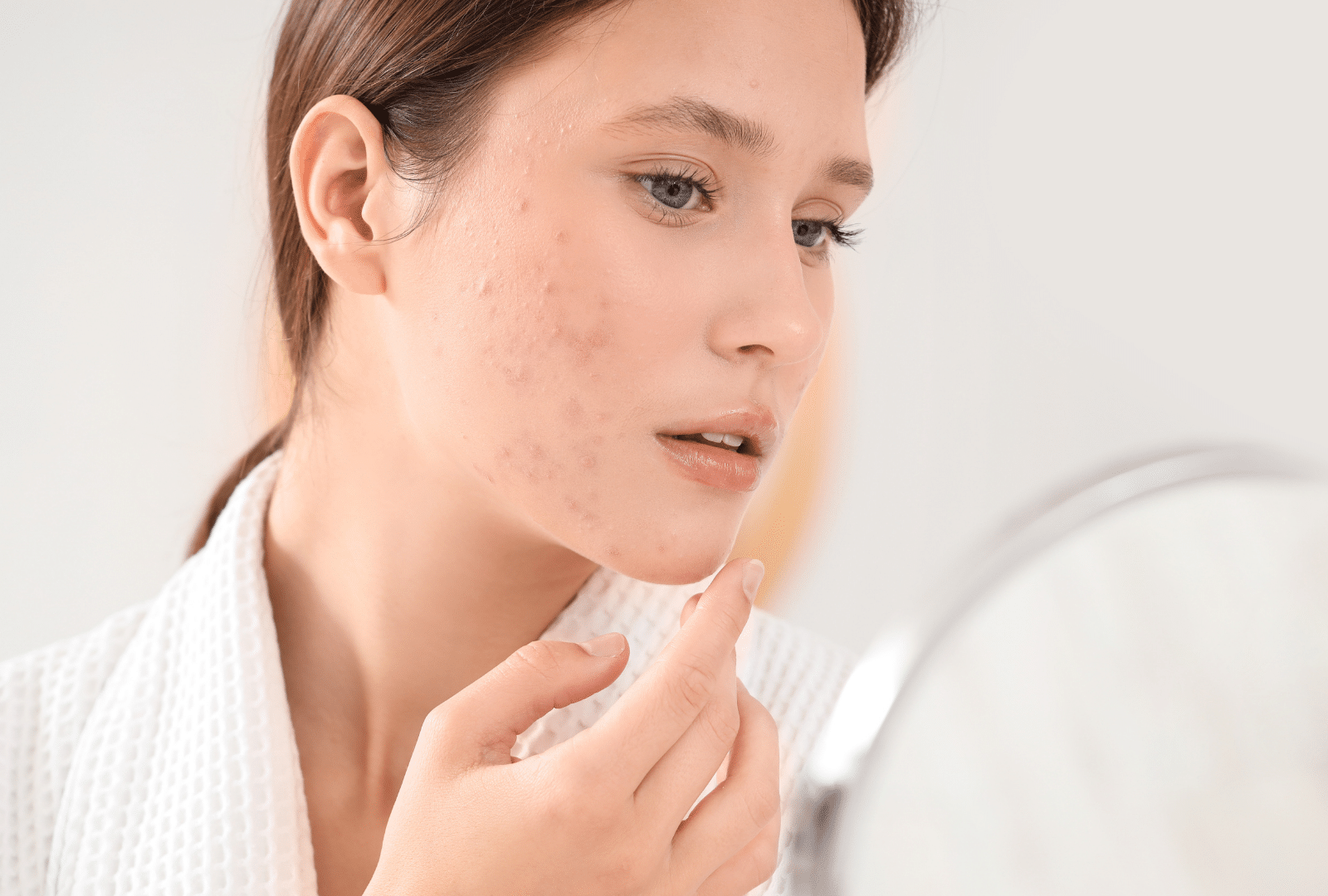 Femme examinant sa peau dans un miroir